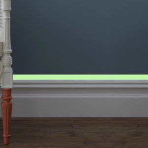 Close-up of luminous safety tape on baseboard providing night glow guidance in home