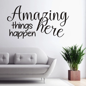 Modern wall sticker featuring 'Amazing things happen here' text above a gray sofa