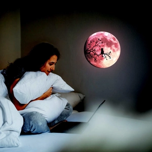 Luminous pink moon wall sticker with cat silhouette in a cozy bedroom night scene