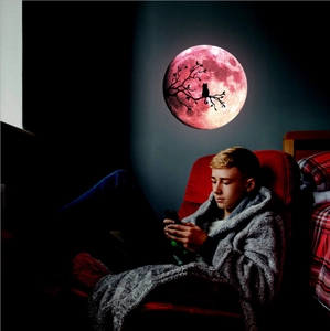 Luminous pink moon wall sticker with cat silhouette glowing in a dark room environment