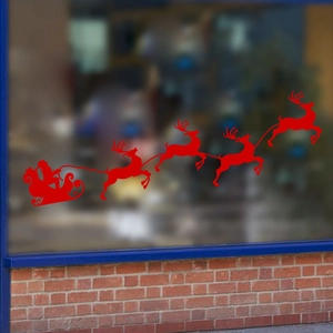 Red Christmas window decal featuring Santa Claus with a reindeer sleigh on a glass window