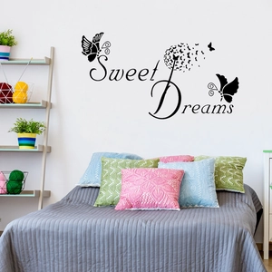 Black Sweet Dreams wall decal with dandelion and butterflies above a cozy bedroom bed
