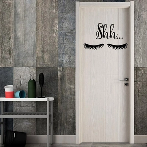 Detail of minimalist black eyelash wall decal with Shh text on a white wooden door