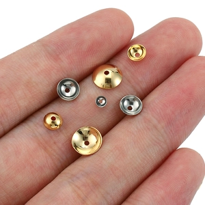 Gold and silver stainless steel bead caps for jewelry making shown on a palm for scale