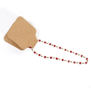 Rote quadratische Perlenkette mit goldenen Akzenten auf braunen Kraftpapier-Hängekarten