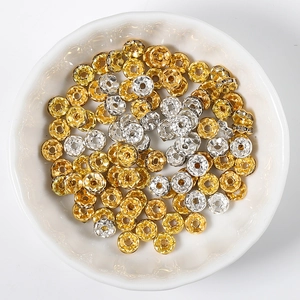 Mixed gold and silver 14K gold-filled flower wheel spacer beads in a white ceramic dish