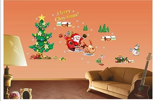 Detail of Christmas wall stickers featuring Santa, tree and cabins on orange wall