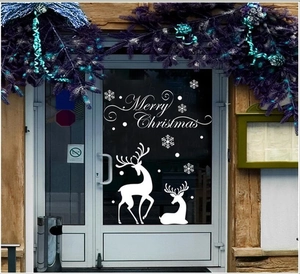 White Merry Christmas window decals featuring snowflakes and reindeer on a store glass door