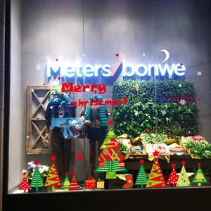 Close-up of festive Christmas window decals on a store front glass with holiday trees