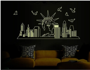 Luminous NYC skyline wall decals glowing light green above yellow sofa in a dark room