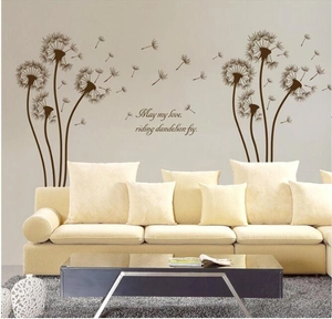 Black dandelion wall sticker with artistic quote above a modern beige sofa for home decor