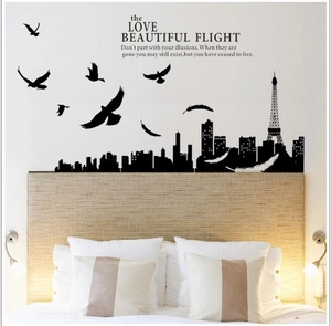 Paris skyline wall decal with Eiffel Tower and flying birds above a bedroom headboard