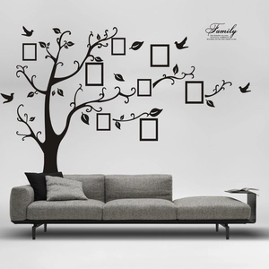 Large black family tree wall decal with photo frames and quote above a grey sofa