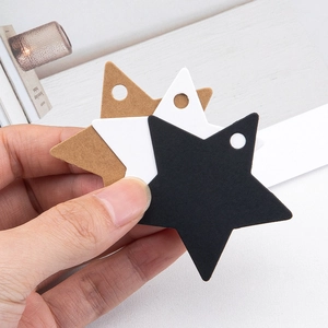 Hand holding star-shaped kraft paper gift tags in brown, white and black colors