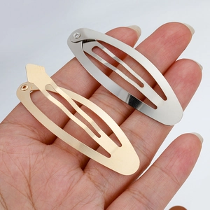 Klassieke ovale metalen BB-haarclips in goud en zilver getoond op de hand voor maat
