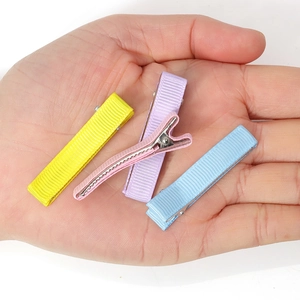 Fermagli per capelli colorati in nastro grosgrain per bambine mostrati sul palmo