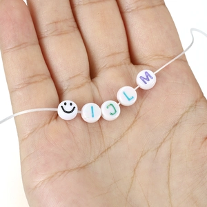 DIY white acrylic round alphabet beads for jewelry making shown on elastic string
