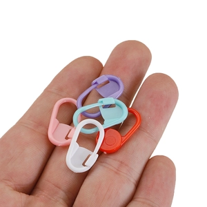 Set of 100 colorful plastic stitch markers for knitting held in palm for scale