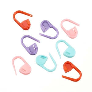 Assorted colorful plastic stitch markers for knitting and DIY weaving tools on white background
