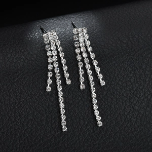 Sparkling silver tassel drop earrings with crystals on a black leather background