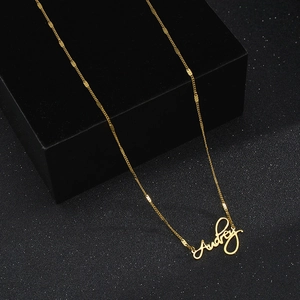 Customized golden stainless steel name necklace with Audrey cursive pendant on black background