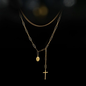 Dettaglio macro della collana a doppio strato in oro 14K con croce e medaglia