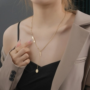 Dettaglio della collana a strati in oro 14K con croce e ciondolo bussola su modella