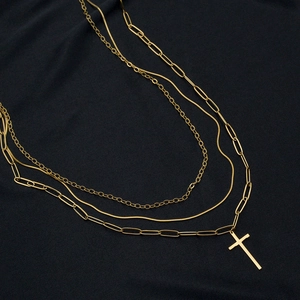 Dettaglio della collana a strati dorata con pendente a croce su tessuto nero strutturato