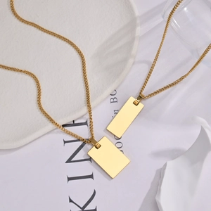 Detail of minimalist gold-plated rectangular pendant necklaces on an aesthetic tray