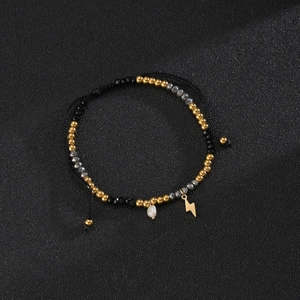 Detail of beaded bracelet with black facets, pearls, and lightning bolt charm on cord