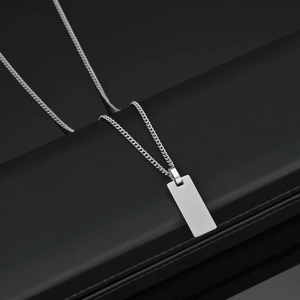 Detailed macro view of a polished stainless steel square dog tag pendant on a Cuban chain