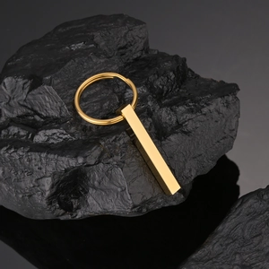 Dettaglio macro del portachiavi rettangolare dorato lucido su trama di roccia minerale nera