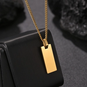 Close-up of golden rectangular dog tag pendant on textured black display stand