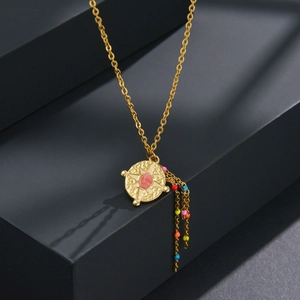 Detail of golden necklace with starburst compass pendant and multi-color beaded tassels
