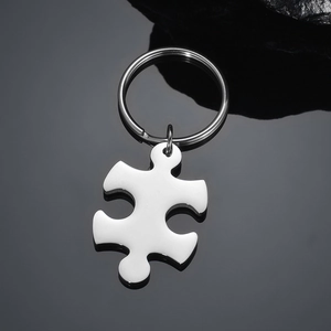 Close-up of polished silver puzzle piece keychain on reflective black surface