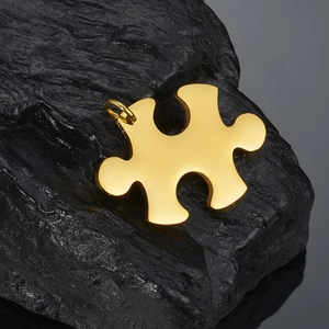 Macro shot of a golden puzzle pendant on dark stone, showcasing polished metal texture