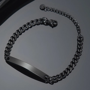 Macro view of polished black stainless steel Cuban link bracelet with curved ID plate