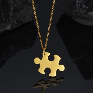 Close-up of a gold-plated puzzle piece pendant with polished S925 finish on black stone