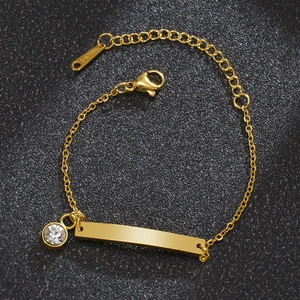 Detalle de pulsera infantil de acero dorado con placa curva y piedra de circón brillante