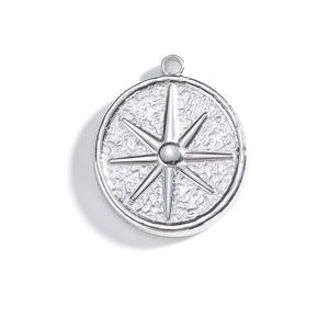 Détail d'un pendentif rond en acier inoxydable argenté avec étoile boussole et texture martelée