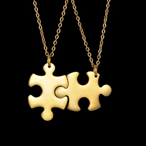 Macro detail of complementary gold puzzle piece pendants with polished stainless steel finish