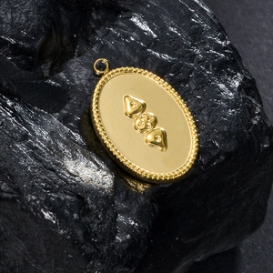 Gros plan d'un pendentif ovale en or avec des motifs abstraits embossés sur pierre sombre