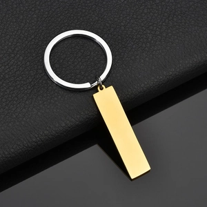 Polished silver key ring with gold rectangular charm on black textured leather surface