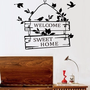 Stickers muraux Welcome et Sweet Home avec oiseaux et feuilles sur un mur blanc de salon