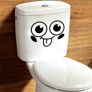 Close-up of a creative cartoon smiley face sticker on a white ceramic toilet tank surface