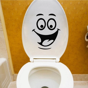 Detail shot of a funny black smile emoji sticker applied to a white toilet lid surface