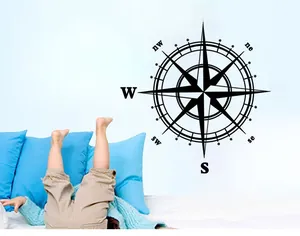 Detail of compass wall sticker featuring directional markers in black vinyl on bedroom wall