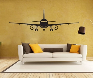Front view of large black airplane silhouette wall sticker above a modern living room sofa