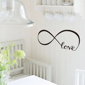 Detail of black Infinite Love wall sticker on a white wooden panel in a bright dining area