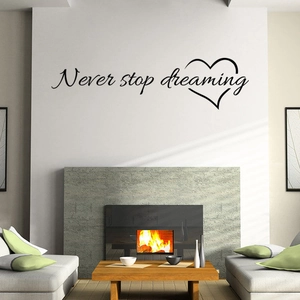 Black 'Never stop dreaming' wall sticker with a hand-drawn heart above a modern sofa